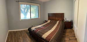 Bedroom featuring dark wood-style flooring and baseboards