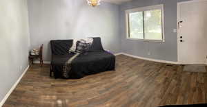 Living area featuring dark wood-style floors and baseboards