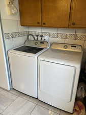 Laundry area featuring cabinet space, independent washer and dryer, and light tile patterned floors