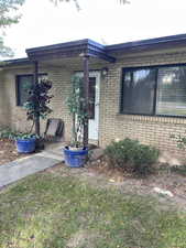 Property entrance featuring brick siding and a lawn
