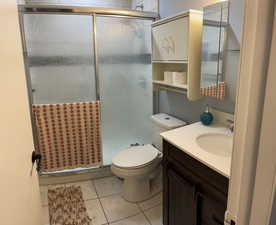 Full bathroom featuring a shower stall, vanity, and light tile patterned floors