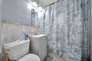 Bathroom with tile walls, vanity, and a shower with shower curtain