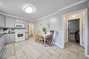 Kitchen with gray cabinets, white appliances, crown molding, decorative backsplash, and wood tiled floors
