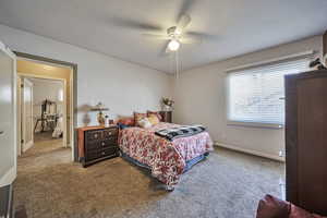Carpeted bedroom with ceiling fan and baseboards
