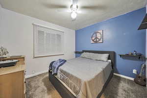 Bedroom with carpet flooring, a ceiling fan, and a textured ceiling