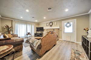 Living area featuring ornamental molding, recessed lighting, light wood-style flooring, and a textured ceiling