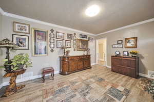 Sitting room featuring a textured ceiling, ornamental molding, and light wood-type flooring