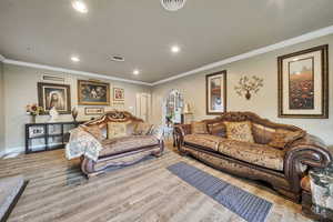Living area featuring arched walkways, ornamental molding, recessed lighting, and wood finished floors