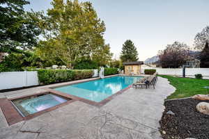 View of pool featuring a fenced backyard, a patio area, an in-ground hot tub, an outdoor structure, and a water slide