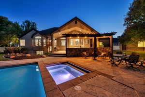 Back of property featuring a patio, an in-ground hot tub, outdoor dining area, an outdoor pool
