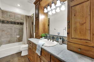 Bathroom with vanity, shower / bath combo, and decorative backsplash