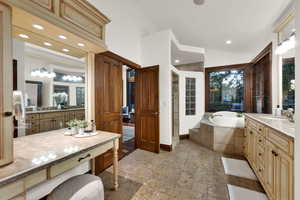 Full bathroom with a garden tub, vanity, stone tile flooring, recessed lighting, and vaulted ceiling