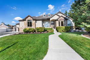 View of front of house with stone siding, stucco siding, a gate, and a garage