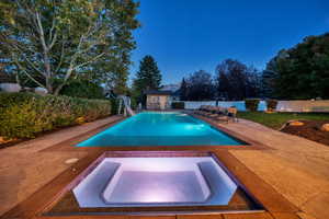 View of pool with a water slide, an in-ground hot tub, a patio area, and a fenced backyard