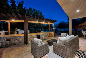 Patio at night featuring a pergola, exterior kitchen, a patio area, and an outdoor living space