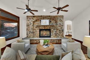 Living area featuring a stone fireplace & vaulted ceiling