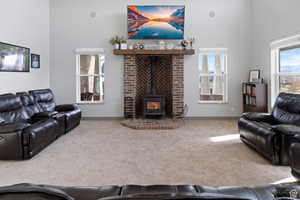 Living area featuring a wood stove, carpet floors, and a high ceiling