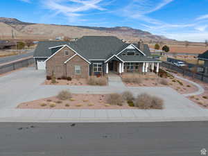 View of front of house with driveway, a mountain view, brick siding, and covered porch