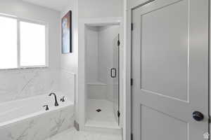 Full bathroom with a stall shower, a garden tub, and marble look tile flooring