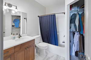 Bathroom with shower / bathtub combination with curtain, vanity, and a spacious closet