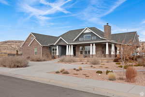 Craftsman house with a porch, brick siding, a chimney, and a shingled roof
