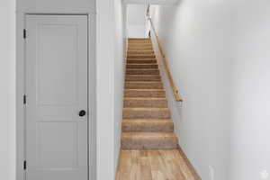 Stairway with wood finished floors and baseboards
