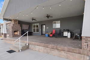 View of patio featuring an outdoor brick fireplace, a ceiling fan, and grilling area