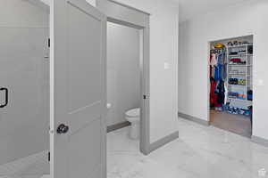 Full bathroom featuring a shower stall, light marble finish flooring, and a spacious closet