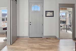 Entrance foyer with a barn door, light carpet, and light wood-style floors