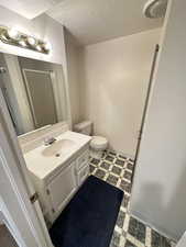 Bathroom featuring vanity, a textured ceiling, a stall shower, and dark flooring