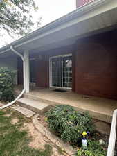 Entrance to property with a porch and brick siding