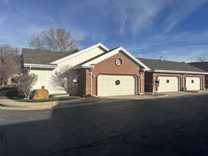 Single story home featuring brick siding, a shingled roof, driveway, and an attached garage