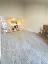 Unfurnished living room with carpet flooring, high vaulted ceiling, and a fireplace