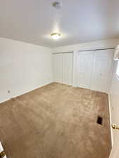 Unfurnished bedroom featuring two closets, carpet flooring, and a textured ceiling