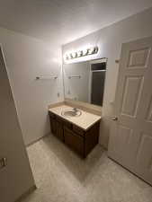 Primary Bathroom featuring vanity, a textured ceiling, and a shower with shower door