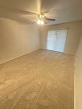 Unfurnished bedroom featuring ceiling fan, a textured ceiling, and light colored carpet