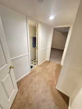 Corridor featuring light carpet and a textured ceiling