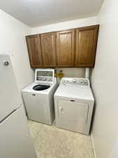 Laundry area with cabinet space, washer and dryer, and a textured ceiling