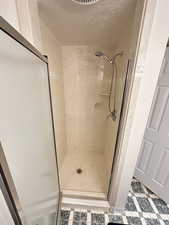 Full bath featuring a textured ceiling and a shower stall
