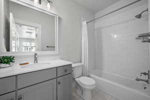 Full bath featuring shower / bath combo with shower curtain, vanity, and light tile patterned floors