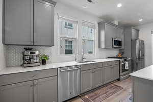 Kitchen featuring gray cabinetry, appliances with stainless steel finishes, tasteful backsplash, light stone counters, and recessed lighting