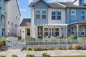 View of front of property with a shingled roof, a fenced front yard, and a patio