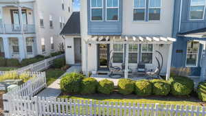 Rear view of property with a pergola, roof with shingles, a gate, stucco siding, and a patio area