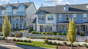 Traditional-style house featuring a fenced front yard, a shingled roof, a residential view, and board and batten siding