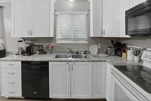 Kitchen featuring black appliances, white cabinetry, and light countertops