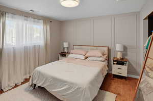 Bedroom with wood finished floors and a decorative wall