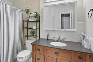 Bathroom featuring decorative backsplash, vanity, and a shower with curtain