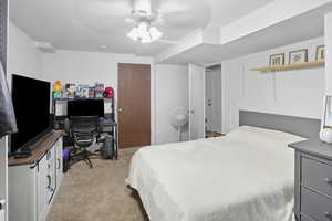 Bedroom featuring an office area, light colored carpet, and ceiling fan