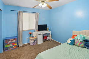 Carpeted bedroom featuring ceiling fan and baseboards