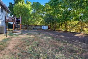 View of yard with stairway, a deck, and a storage unit